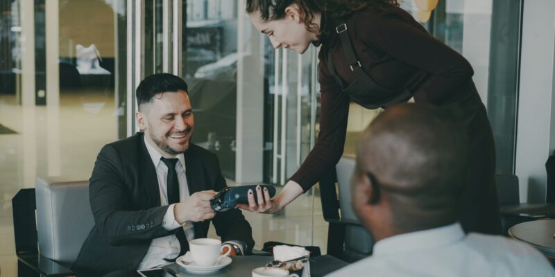 Man pays with credit card at cafe table